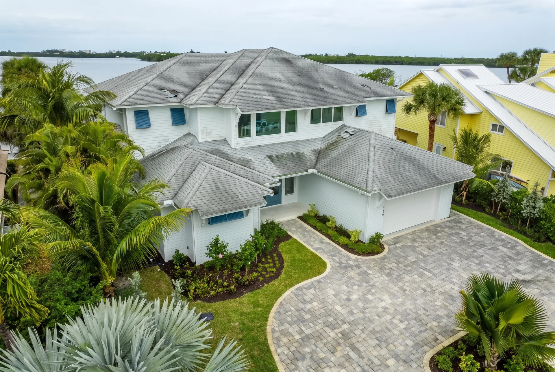 A waterfront home with an old worn shingle roof